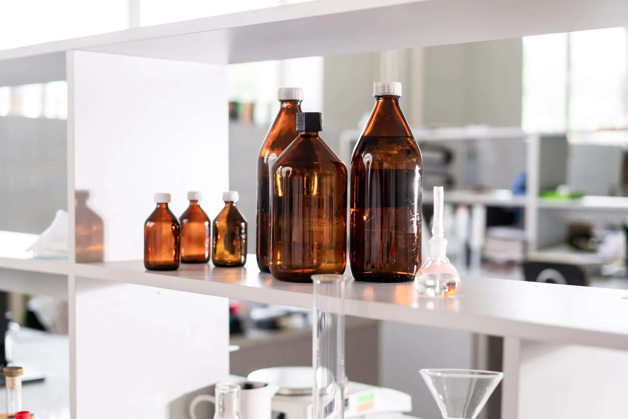 Amber glass laboratory bottles and vials on a bright shelf