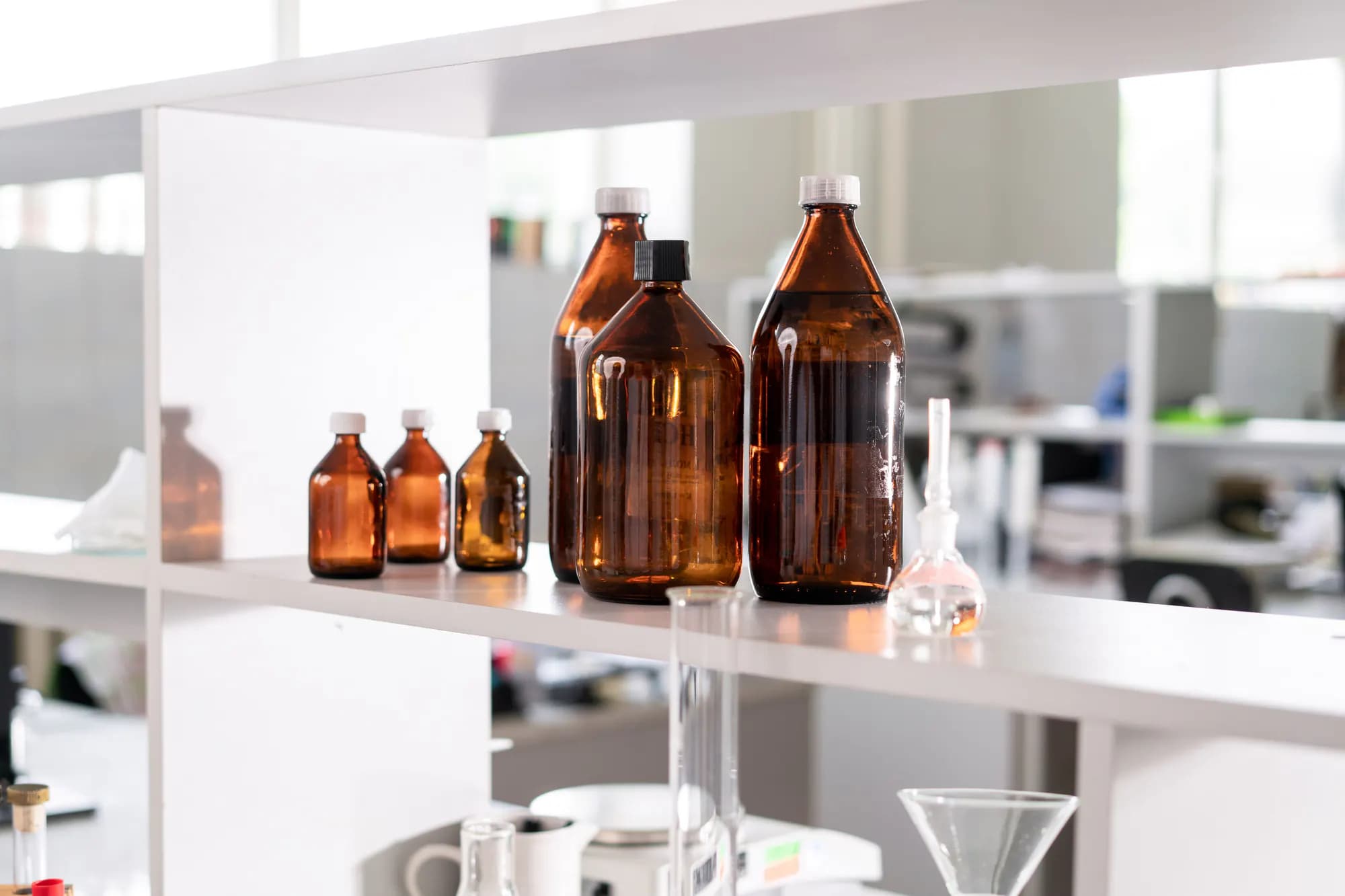 Amber glass laboratory bottles and vials on a bright shelf